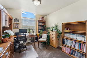 Office area with lofted ceiling, baseboards, and dark colored carpet