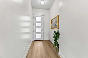 Doorway to outside featuring baseboards and light wood-style flooring