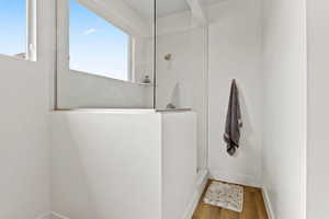 Bathroom featuring walk in shower, wood finished floors, and baseboards