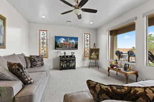 Carpeted living room featuring ceiling fan, baseboards, and recessed lighting