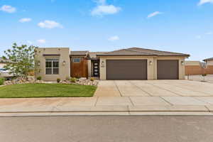View of front of home with an attached garage, a tiled roof, stucco siding, concrete driveway, and a front yard