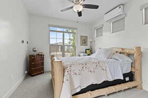 Bedroom featuring a wall mounted AC, carpet flooring, baseboards, and a ceiling fan
