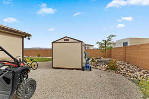 Fenced backyard featuring a storage shed and an outdoor structure