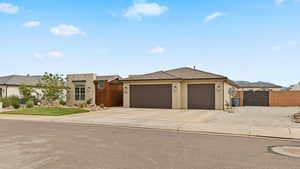 View of front of home featuring stucco siding, driveway, an attached garage, a gate, and fence