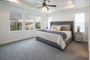 Bedroom with carpet, baseboards, ceiling fan, visible vents, and a raised ceiling