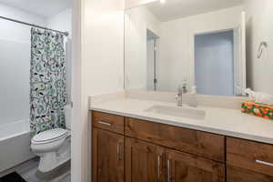 Full bath featuring vanity, toilet, shower / bathtub combination with curtain, and wood finished floors
