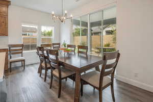 Dining area with a chandelier, wood finished floors, and baseboards