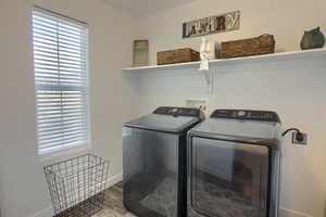 Laundry room featuring baseboards, laundry area, independent washer and dryer, and wood finished floors