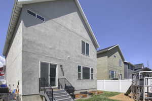 Rear view of property with fence, stucco siding, a playground, and central AC