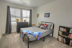 Bedroom with light colored carpet, baseboards, and visible vents