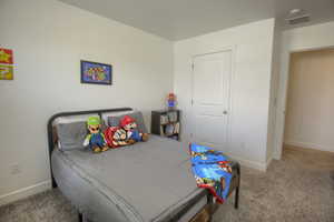 Carpeted bedroom featuring baseboards and visible vents
