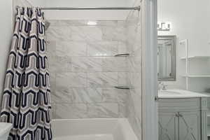 Bathroom featuring vanity, shower / bath combo, and toilet
