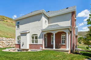 View of front of home featuring a shingled roof, a front lawn, brick siding, stucco siding, and covered porch