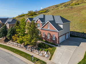 View of front of house featuring brick siding, a garage, roof with shingles, and concrete driveway