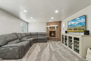 Living room with carpet, a brick fireplace, and recessed lighting