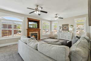 Carpeted living room with baseboards, visible vents, a wealth of natural light, and a fireplace