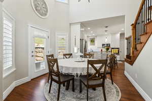 Dining room with dark wood-style flooring, stairs, and a wealth of natural light