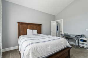 Carpeted bedroom with high vaulted ceiling and baseboards