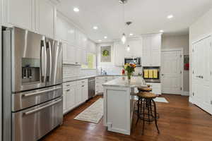 Kitchen with white cabinetry, appliances with stainless steel finishes, a sink, and tasteful backsplash
