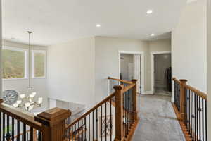 Hallway with carpet, a notable chandelier, recessed lighting, and an upstairs landing