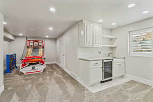 Bar with wine cooler, indoor wet bar, baseboards, recessed lighting, and a sink