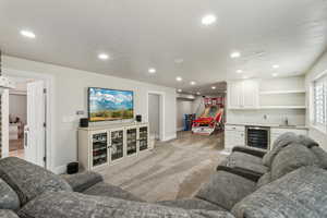 Living room featuring light colored carpet, recessed lighting, wet bar, baseboards, and wine cooler