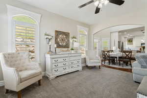 Sitting room featuring a healthy amount of sunlight, arched walkways, ceiling fan, and carpet