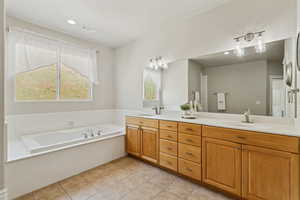Full bathroom with a sink, double vanity, tile patterned floors, visible vents, and a garden tub