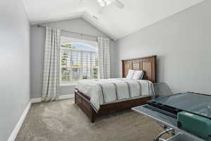 Carpeted bedroom with a ceiling fan, baseboards, visible vents, and lofted ceiling