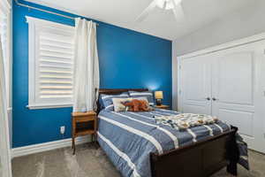 Carpeted bedroom with baseboards, ceiling fan, and a closet