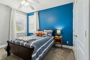 Carpeted bedroom featuring visible vents, a ceiling fan, and baseboards