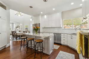 Kitchen featuring white cabinets, a kitchen breakfast bar, stainless steel appliances, decorative backsplash, and a kitchen island