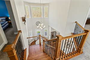 Stairs featuring carpet floors, a high ceiling, a chandelier, and baseboards