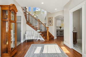 Entrance foyer with stairs, wood finished floors, recessed lighting, arched walkways, and a notable chandelier