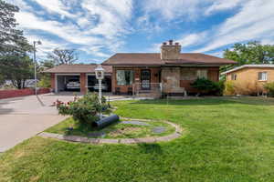 View of front of home featuring covered porch, concrete driveway, a front lawn, and a chimney