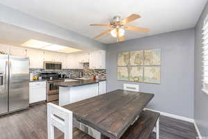 Kitchen featuring stainless steel appliances, dark countertops, a peninsula, and white cabinetry