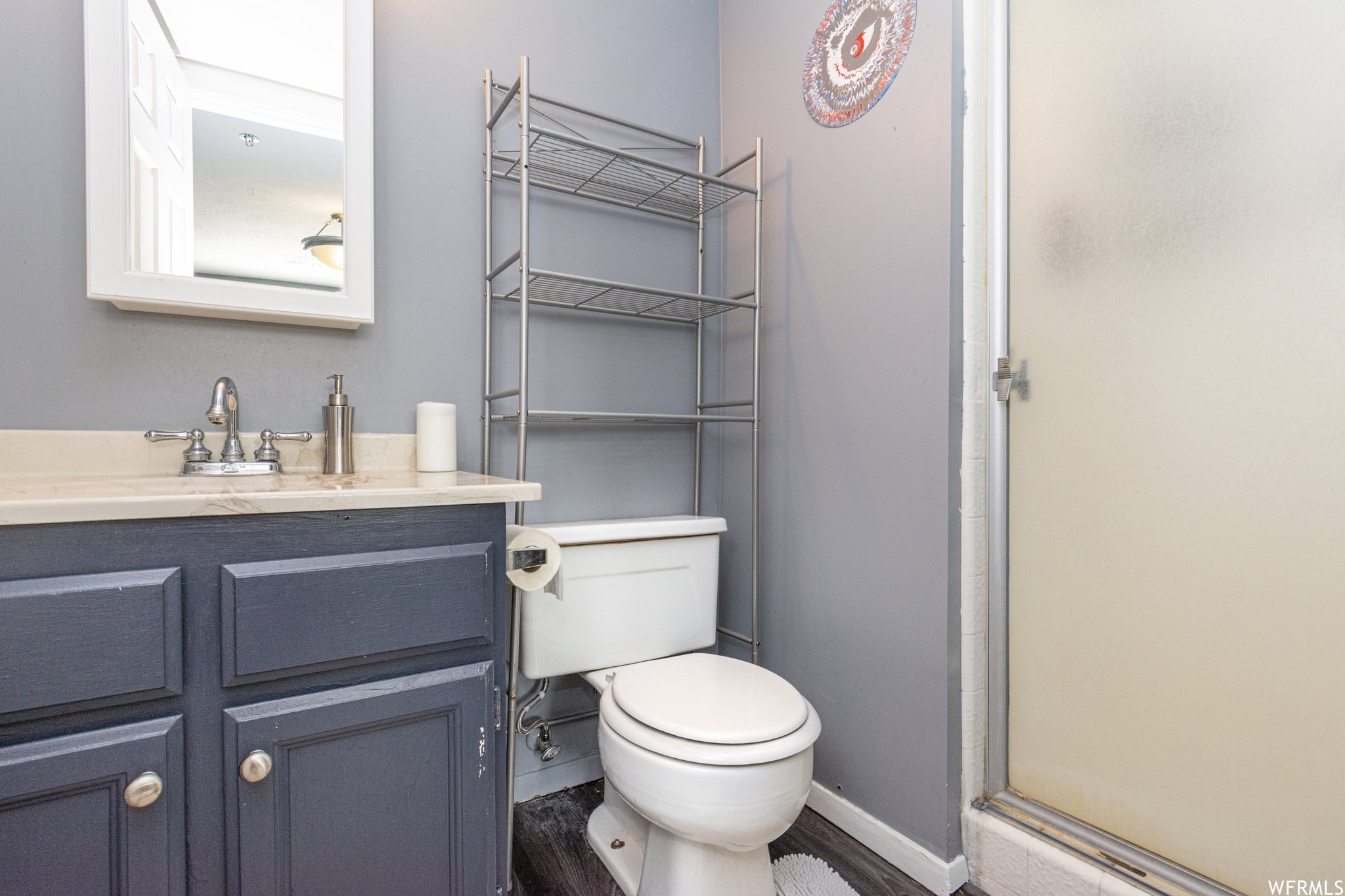 Bathroom featuring a stall shower, vanity, and wood finished floors