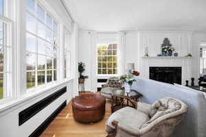 Living room with ornamental molding, a high end fireplace, and wood finished floors