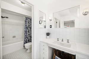 Full bathroom featuring toilet, tile walls, tile patterned floors, and shower / tub combo