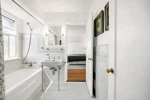 Bathroom featuring bathtub / shower combination, a sink, a wainscoted wall, tile patterned floors, and tile walls