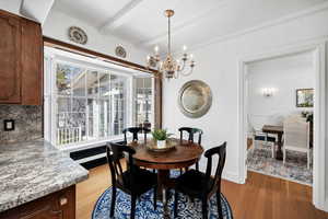 Dining area featuring a chandelier, light wood-style flooring, baseboards, and beam ceiling
