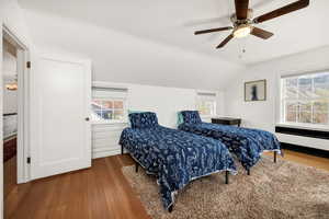 Bedroom featuring lofted ceiling, radiator heating unit, ceiling fan, and wood finished floors