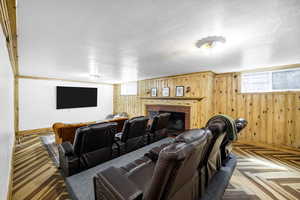 Home theater room with baseboards, wood walls, and a fireplace