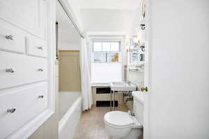 Full bath featuring tile walls, toilet, shower / tub combo with curtain, a sink, and tile patterned flooring