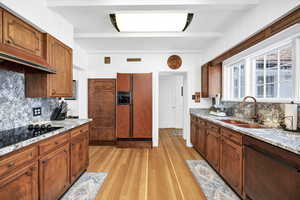 Kitchen with light wood-style flooring, dishwasher, refrigerator with ice dispenser, a sink, and tasteful backsplash