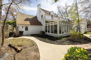 View of home's exterior featuring a chimney, central air condition unit, and a sunroom