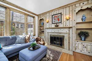 Living room with a premium fireplace, built in features, wood finished floors, and a healthy amount of sunlight