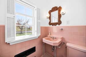 Pink Bathroom featuring toilet, tile walls, a wainscoted wall, and plenty of natural light