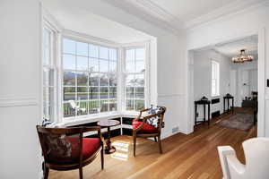 Living area with ornamental molding, light wood-style flooring, visible vents, and a chandelier