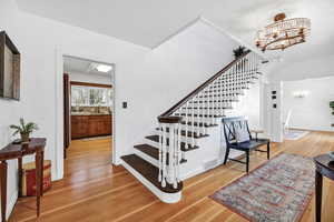 Stairway featuring a notable chandelier, visible vents, and wood finished floors